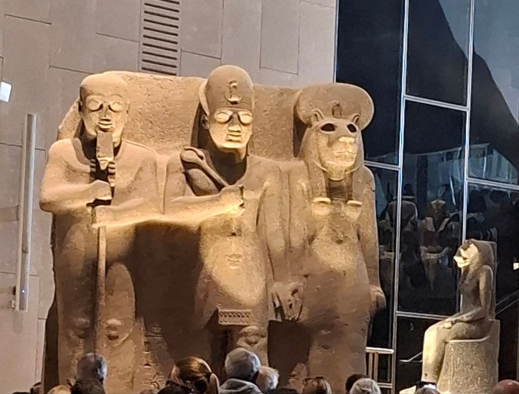 Ancient Egyptian stone statues displayed in the Grand Egyptian Museum, showcasing intricate carvings and details.