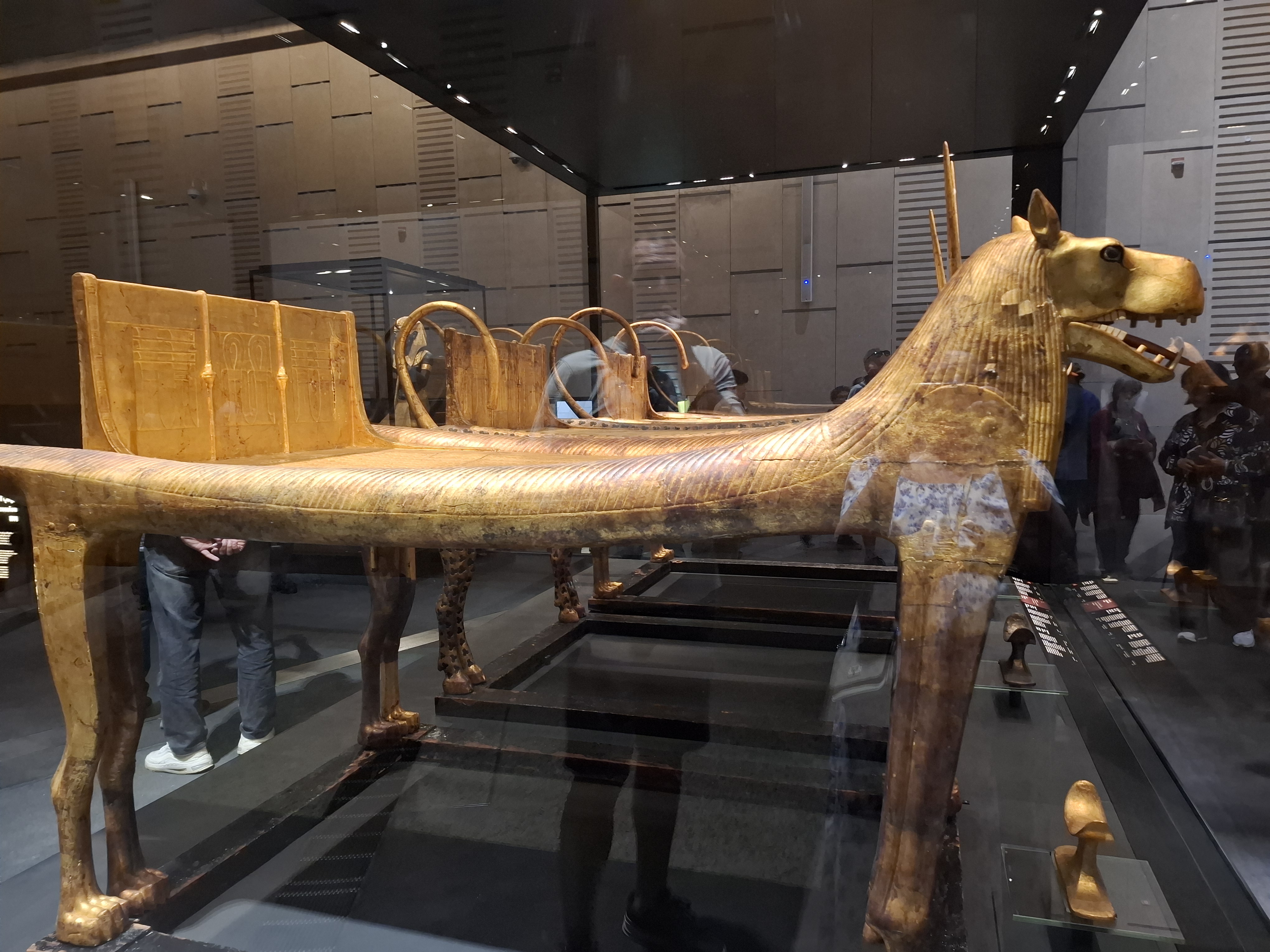 View of a golden funerary couch designed in the shape of a lion found in the Grand Egyptian Museum, showcasing intricate details and ancient Egyptian craftsmanship.